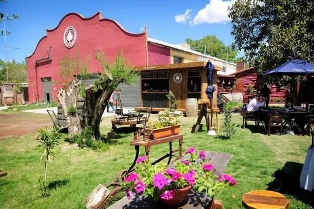 Fachada roja y jardín con mesas al aire libre de Bodega Pulmary